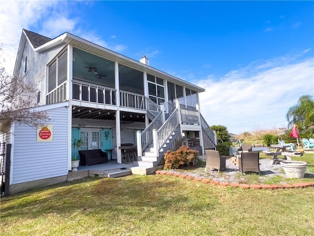 back of house featuring a sunroom, a yard, an outdoor fire pit, and a patio