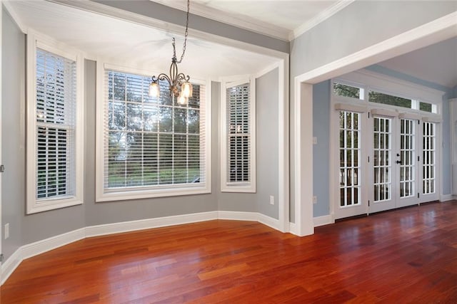 unfurnished dining area featuring dark hardwood / wood-style floors, crown molding, and a chandelier