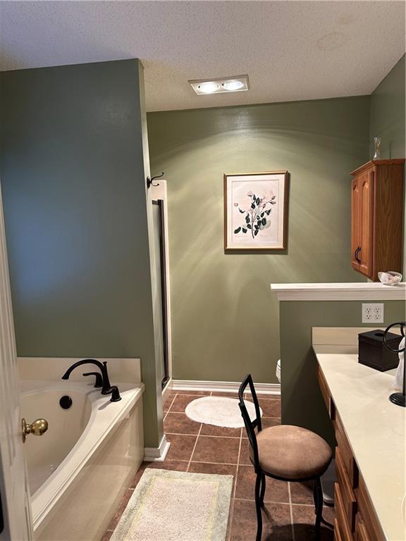 bathroom with vanity, a tub to relax in, a textured ceiling, and tile patterned flooring