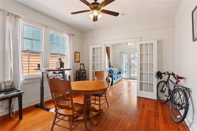 dining room with ceiling fan, wood-type flooring, and french doors