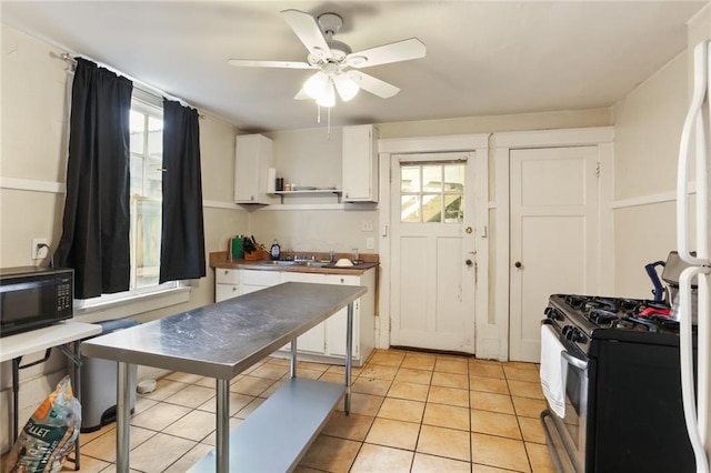 kitchen featuring gas stove, white cabinetry, white refrigerator, light tile patterned flooring, and ceiling fan