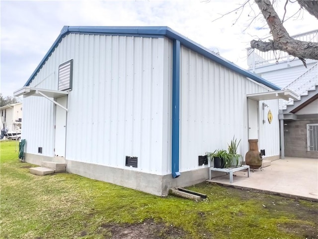 view of side of home featuring board and batten siding, a patio area, and a lawn