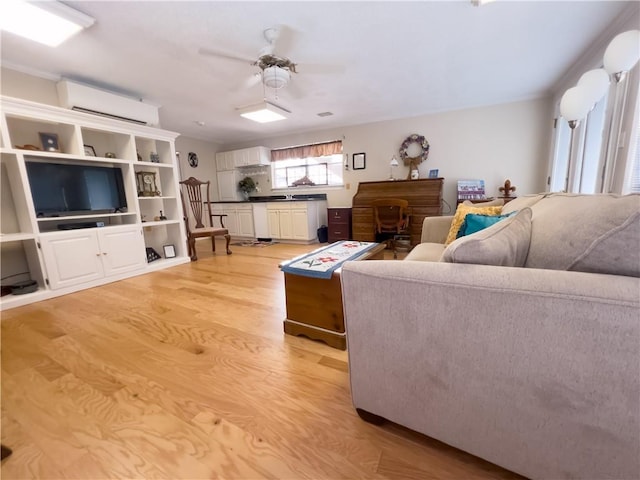 living room with an AC wall unit, ceiling fan, and light wood finished floors