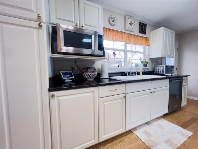 kitchen with a sink, white cabinets, black dishwasher, stainless steel microwave, and dark countertops