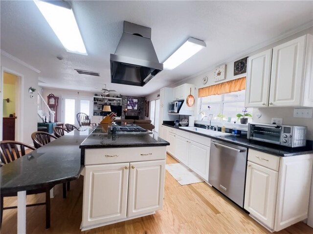 kitchen featuring crown molding, appliances with stainless steel finishes, sink, white cabinetry, and island exhaust hood