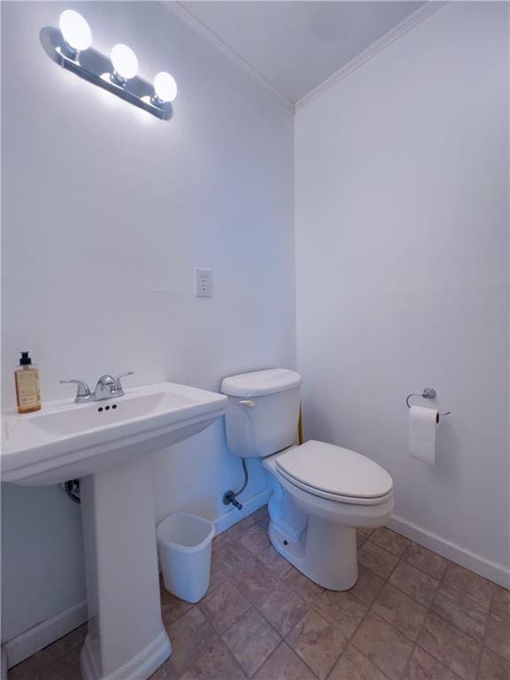 bathroom featuring ornamental molding, baseboards, a sink, and toilet