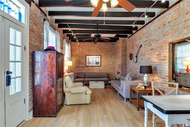 living room featuring beam ceiling, light wood-type flooring, and brick wall