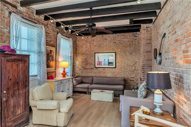 living room featuring brick wall, ceiling fan, track lighting, beam ceiling, and light hardwood / wood-style flooring