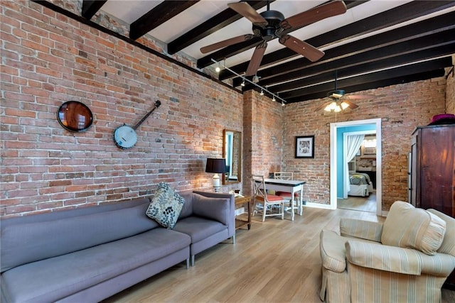 living room with ceiling fan, brick wall, beam ceiling, and light wood-type flooring