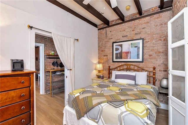 bedroom with ceiling fan, light hardwood / wood-style flooring, beamed ceiling, and brick wall