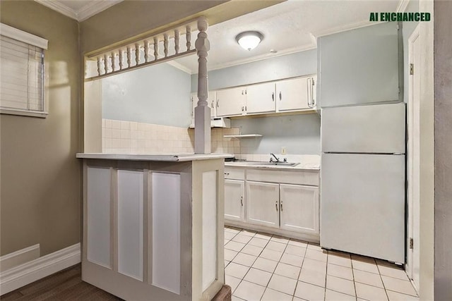 kitchen with white refrigerator, white cabinets, light tile patterned flooring, and ornamental molding