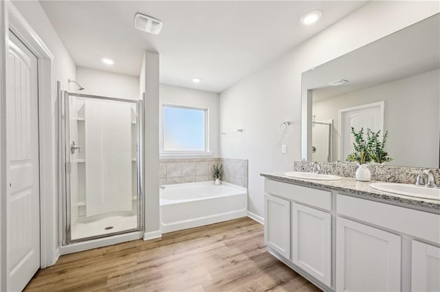 bathroom featuring vanity, wood-type flooring, and plus walk in shower