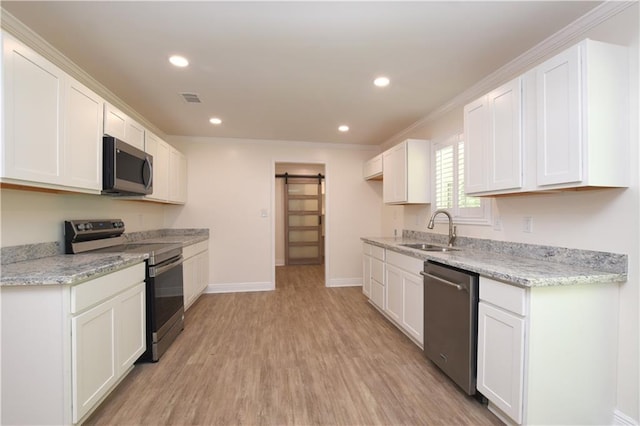 kitchen featuring sink, light stone counters, stainless steel appliances, a barn door, and white cabinets