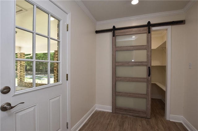 entryway with dark hardwood / wood-style floors, ornamental molding, and a barn door