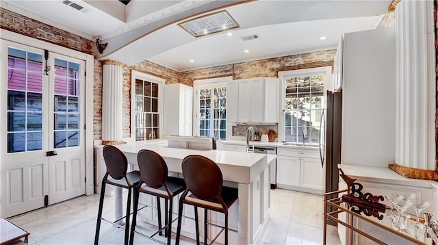 kitchen featuring a kitchen bar, white cabinetry, a kitchen island, stainless steel appliances, and backsplash