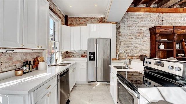 kitchen featuring brick wall, stainless steel appliances, sink, and white cabinets