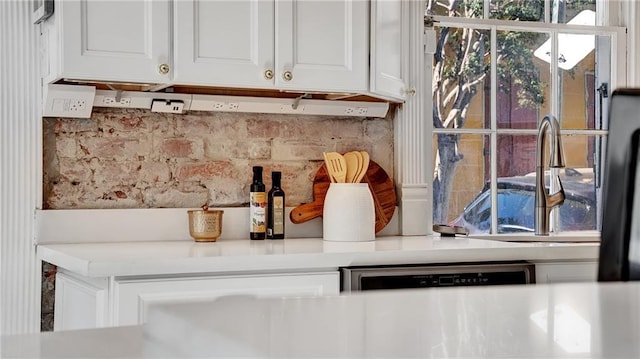 interior details with dishwasher, white cabinets, and decorative backsplash