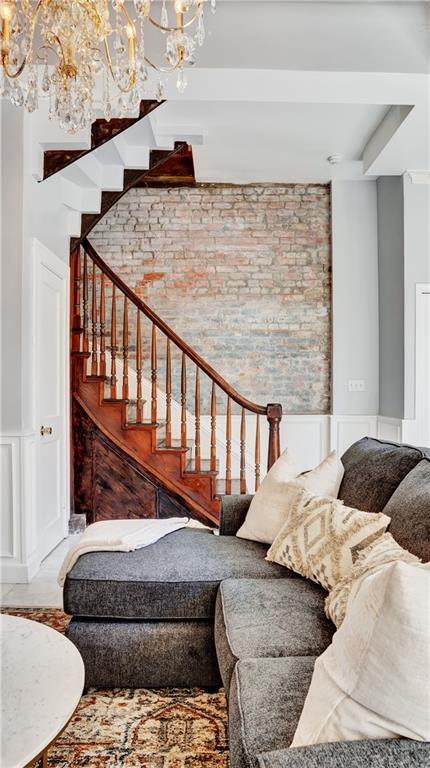 stairway featuring brick wall and an inviting chandelier