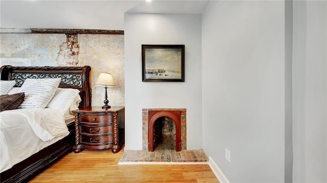 bedroom featuring wood-type flooring and a brick fireplace