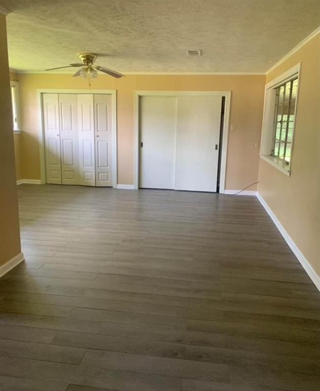 unfurnished bedroom with crown molding, dark wood-type flooring, and ceiling fan