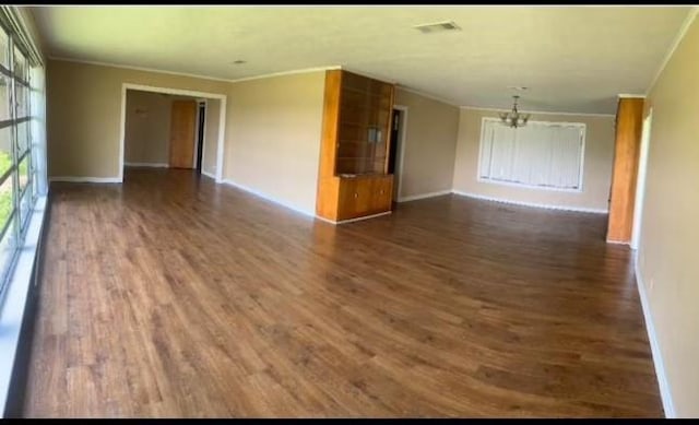 unfurnished room with dark hardwood / wood-style flooring, a notable chandelier, and ornamental molding