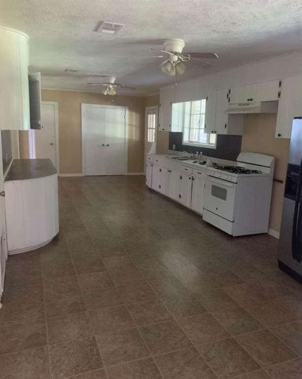 kitchen featuring gas range gas stove, ceiling fan, stainless steel refrigerator, white cabinetry, and a textured ceiling