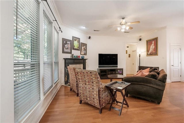 living room featuring ceiling fan, ornamental molding, and light hardwood / wood-style floors