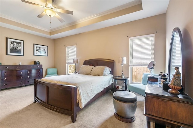 bedroom with light carpet, a tray ceiling, multiple windows, and ceiling fan