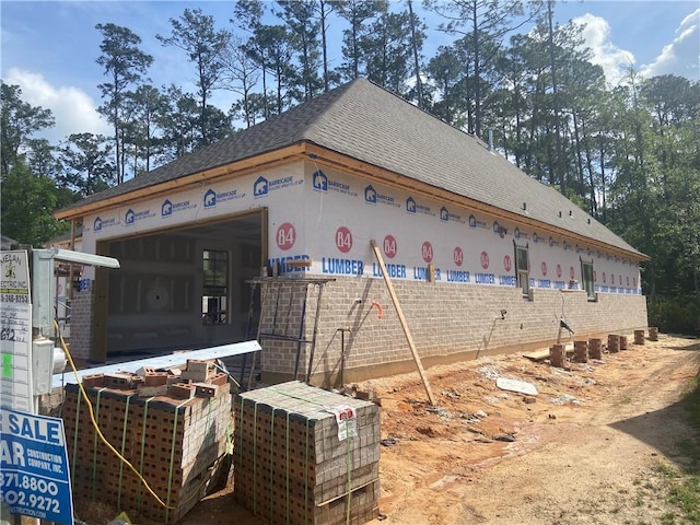 view of property exterior featuring an attached garage and roof with shingles