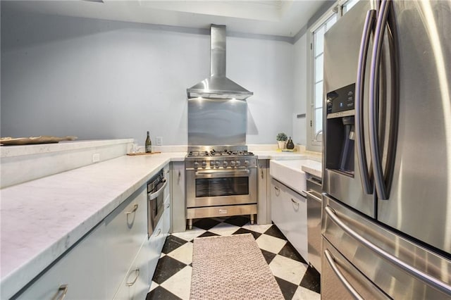 kitchen featuring wall chimney range hood, a tray ceiling, and stainless steel appliances