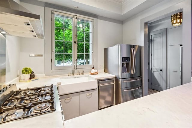 kitchen featuring a raised ceiling, sink, crown molding, gas stovetop, and stainless steel refrigerator with ice dispenser