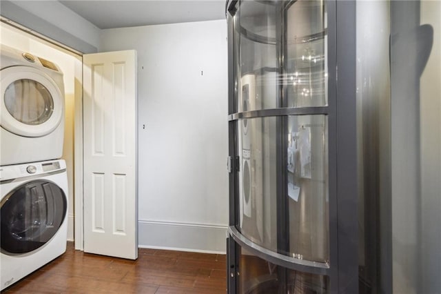 laundry room featuring stacked washer / drying machine and dark wood-type flooring