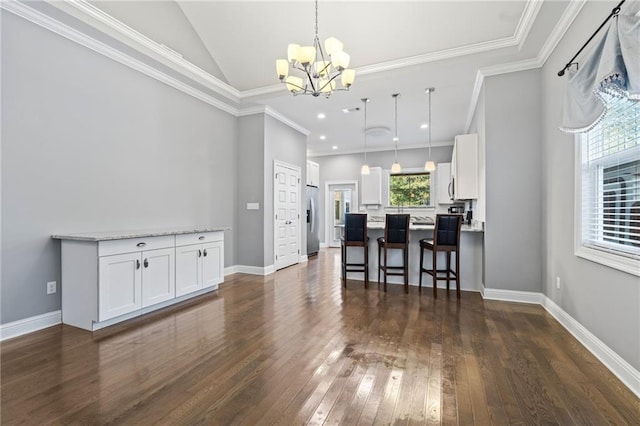 interior space featuring ornamental molding, lofted ceiling, dark hardwood / wood-style floors, and an inviting chandelier