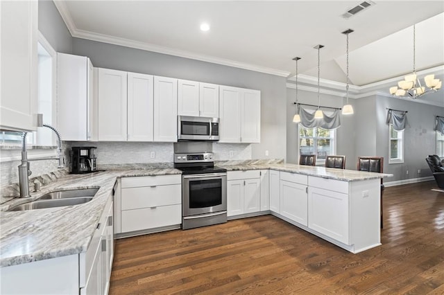 kitchen featuring sink, appliances with stainless steel finishes, white cabinets, vaulted ceiling, and kitchen peninsula