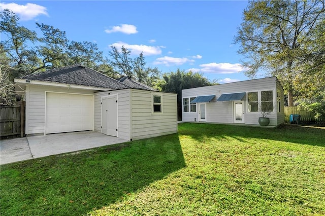 back of house featuring a garage, an outdoor structure, and a lawn