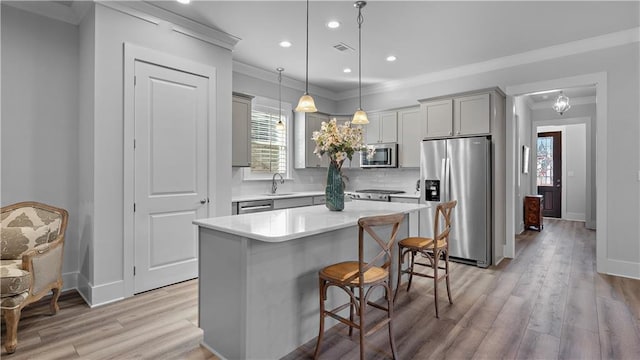 kitchen with sink, crown molding, a center island, appliances with stainless steel finishes, and pendant lighting