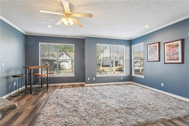 sitting room with ceiling fan, dark wood-type flooring, ornamental molding, and a textured ceiling