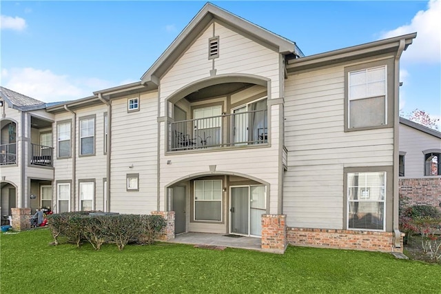 rear view of house with a patio, a balcony, and a lawn