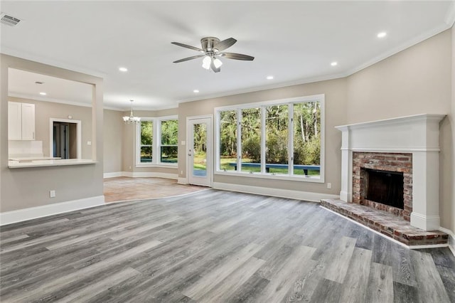 unfurnished living room featuring crown molding, ceiling fan with notable chandelier, a brick fireplace, and light wood-type flooring