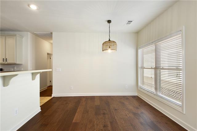 unfurnished dining area with dark wood-style flooring, visible vents, and baseboards