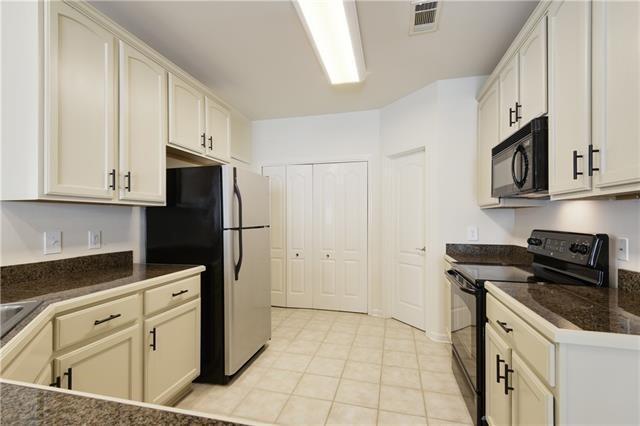 kitchen featuring dark countertops, black appliances, light tile patterned floors, and visible vents