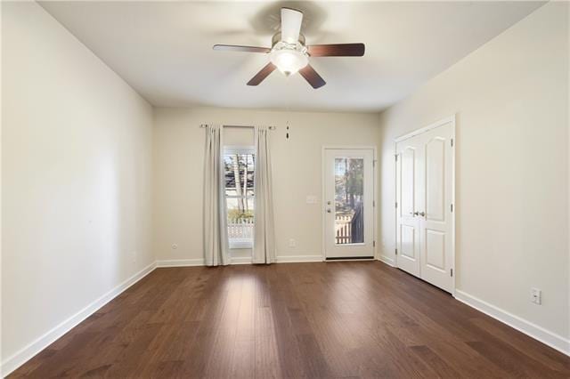 interior space with a ceiling fan, baseboards, and dark wood-type flooring