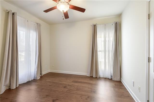 empty room with ceiling fan, dark wood-style flooring, and baseboards