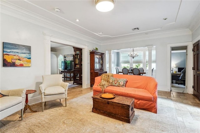 living room featuring ornate columns, ornamental molding, and a chandelier