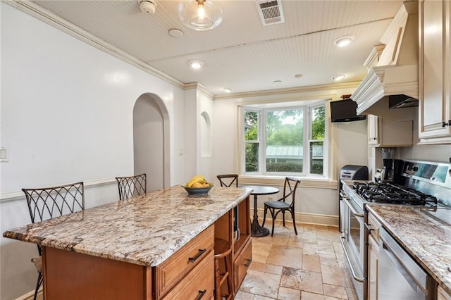 kitchen with a kitchen island, appliances with stainless steel finishes, a breakfast bar, ornamental molding, and light stone counters