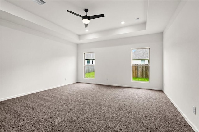 carpeted empty room with ceiling fan and a tray ceiling