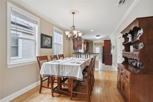 dining space featuring ornamental molding, a notable chandelier, and light wood-type flooring