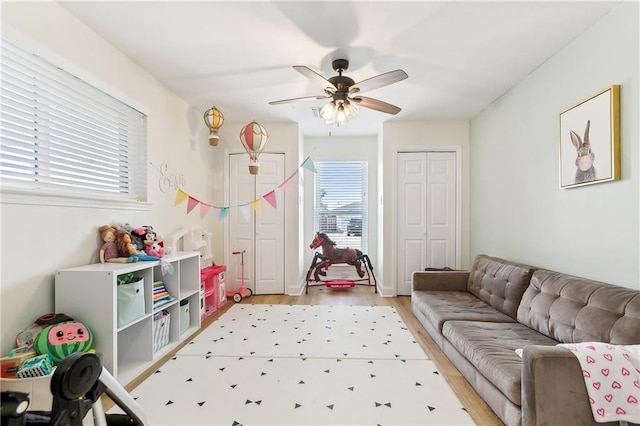 playroom with ceiling fan and light hardwood / wood-style flooring