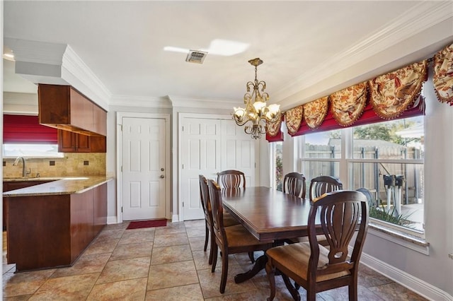 dining space featuring crown molding, plenty of natural light, sink, and an inviting chandelier