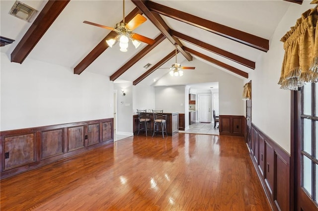 unfurnished living room featuring vaulted ceiling with beams, hardwood / wood-style floors, and ceiling fan